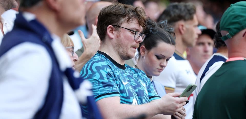 Fans watching a match, focused on their phones