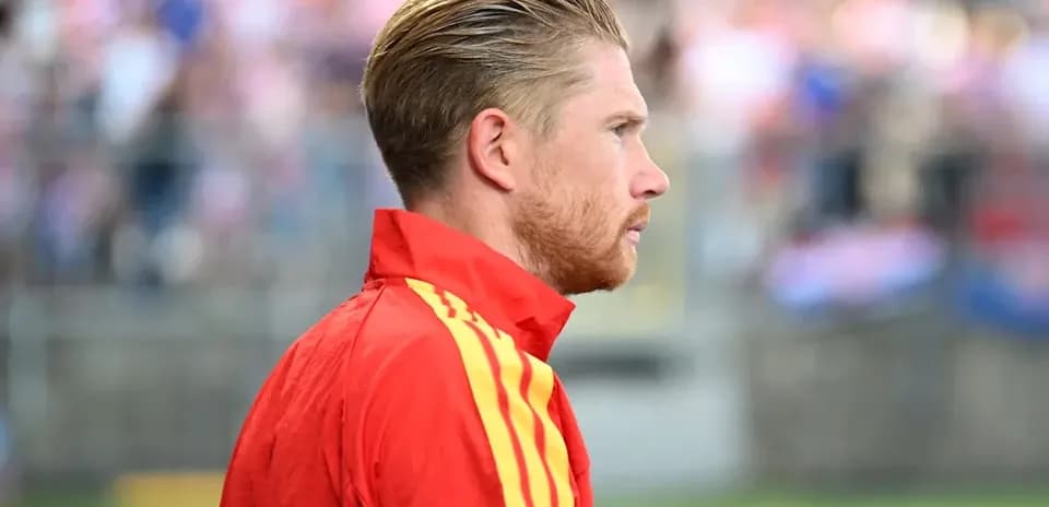 Player in red jacket on sidelines during match