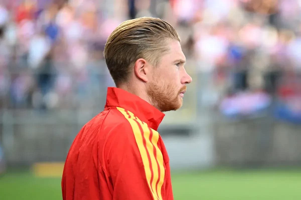 Player in red jacket on sidelines during match