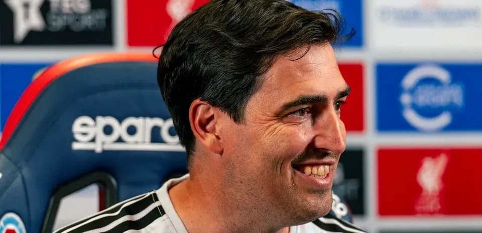 Manager smiling during press conference at podium