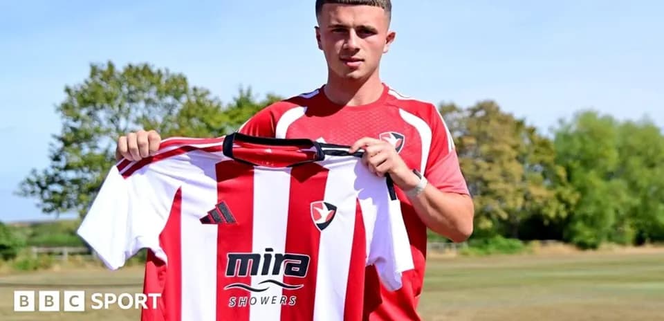 Player holding Cheltenham Town jersey during signing event