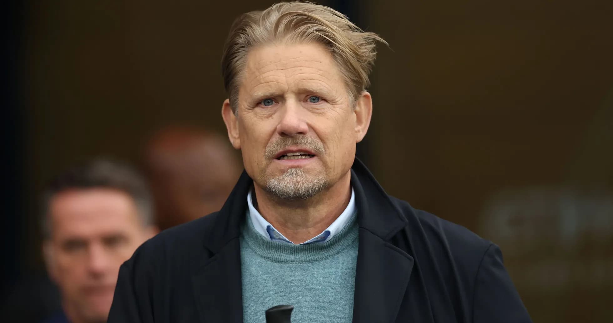 Man in a coat speaking at an event