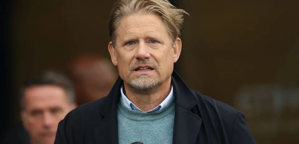 Man in a coat speaking at an event