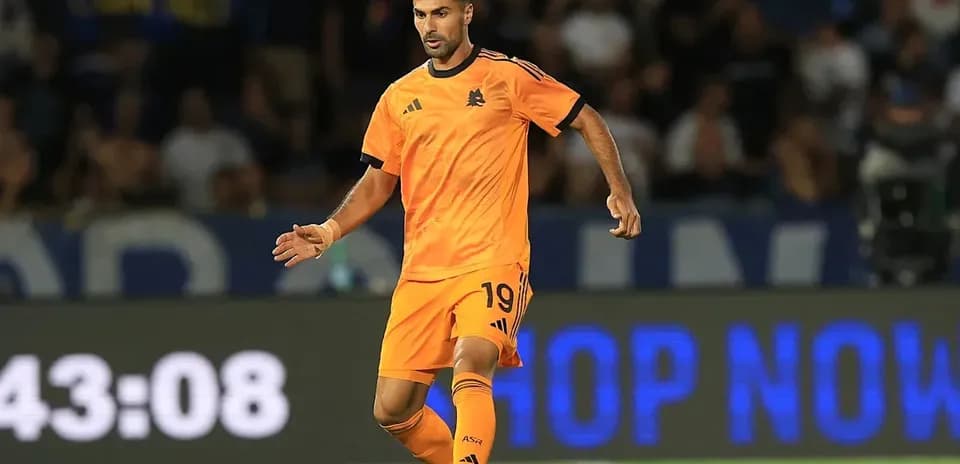 Player in orange kit dribbling the ball on field