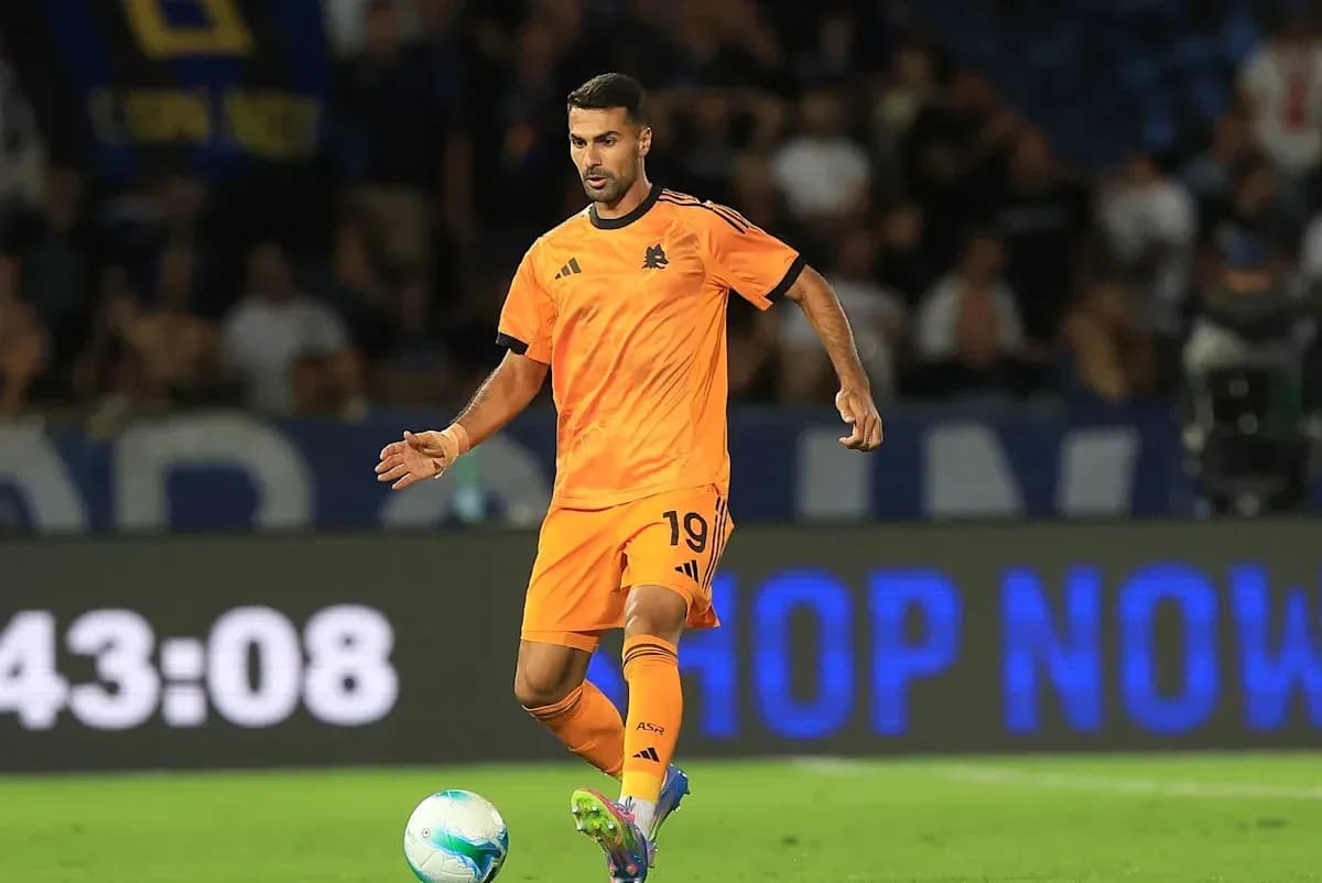 Player in orange kit dribbling the ball on field