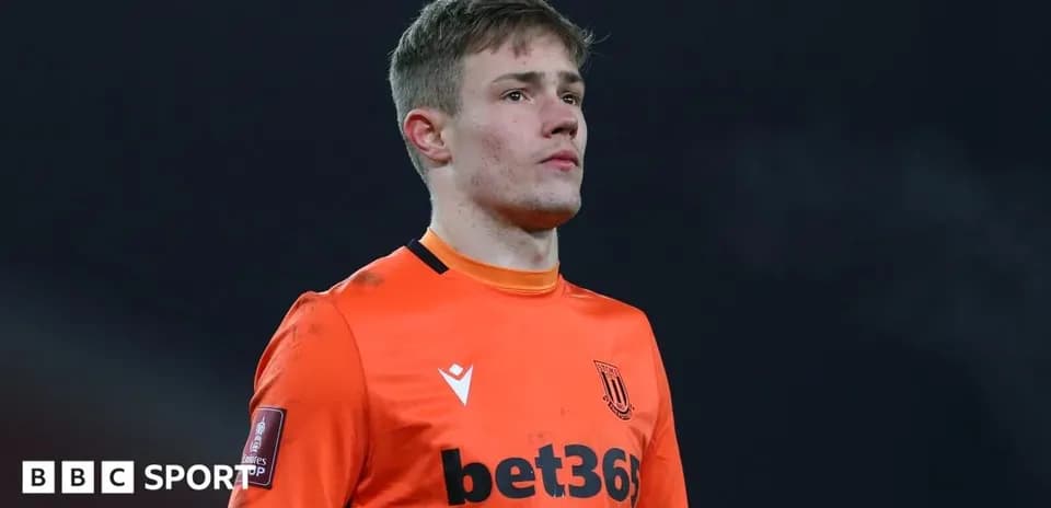 Goalkeeper in orange kit during match warm-up
