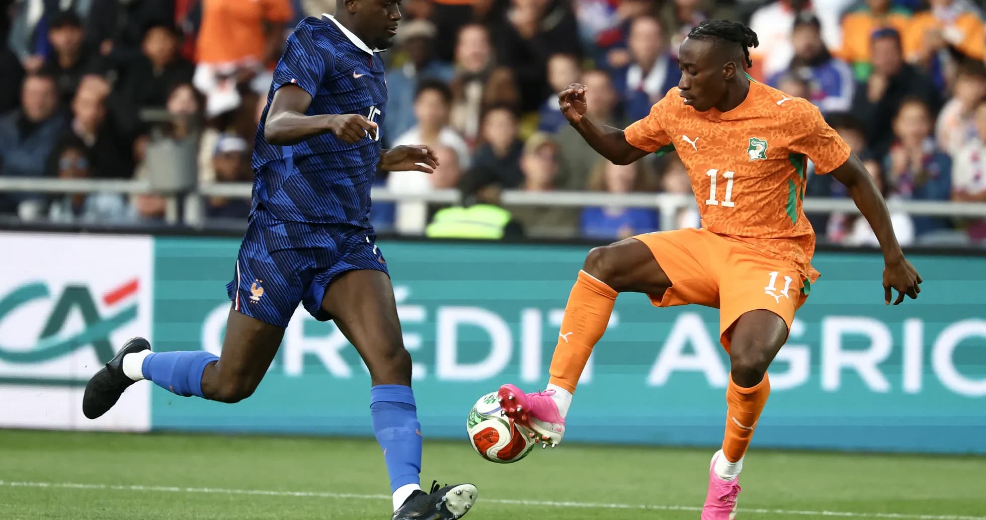 Player in orange dribbling past opponent in blue