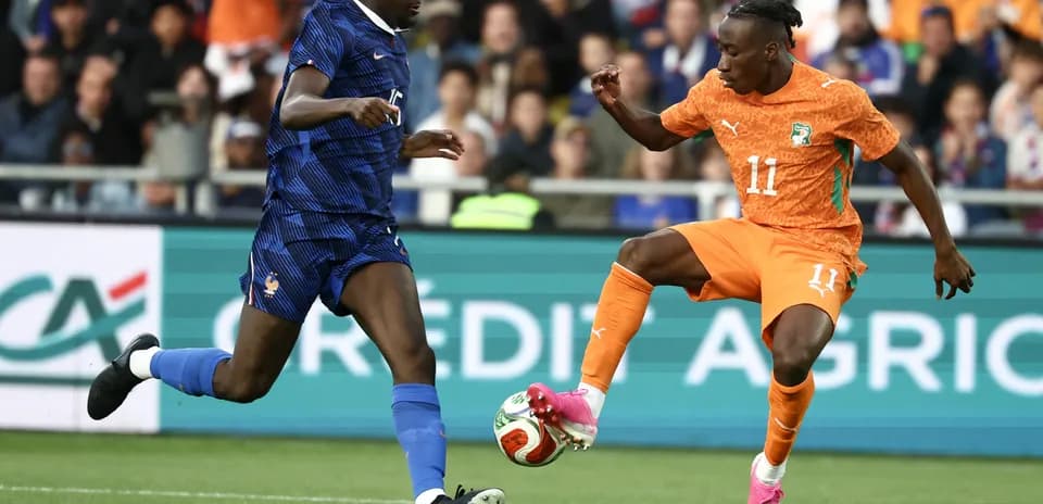 Player in orange dribbling past opponent in blue