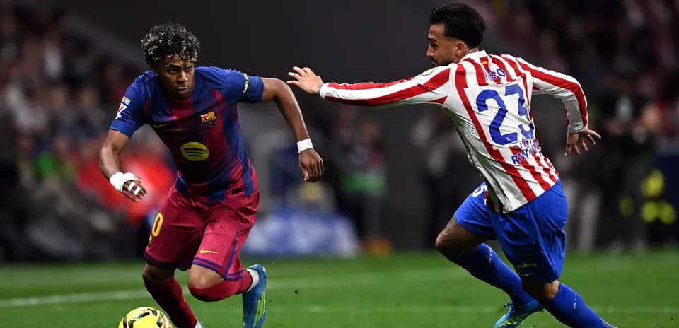 Barcelona player dribbling past Atletico Madrid defender
