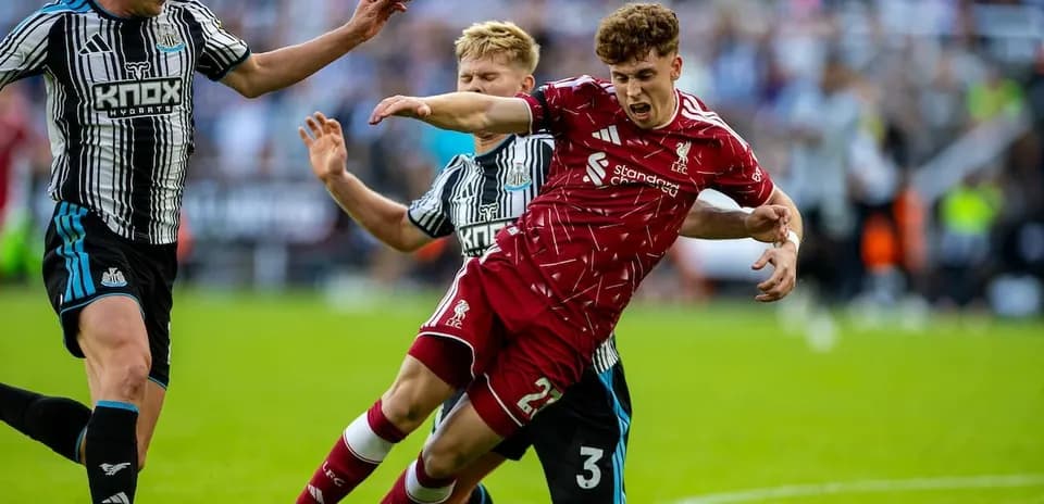Newcastle players challenging Liverpool player on field