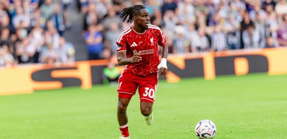 Player in red kit running with soccer ball on field