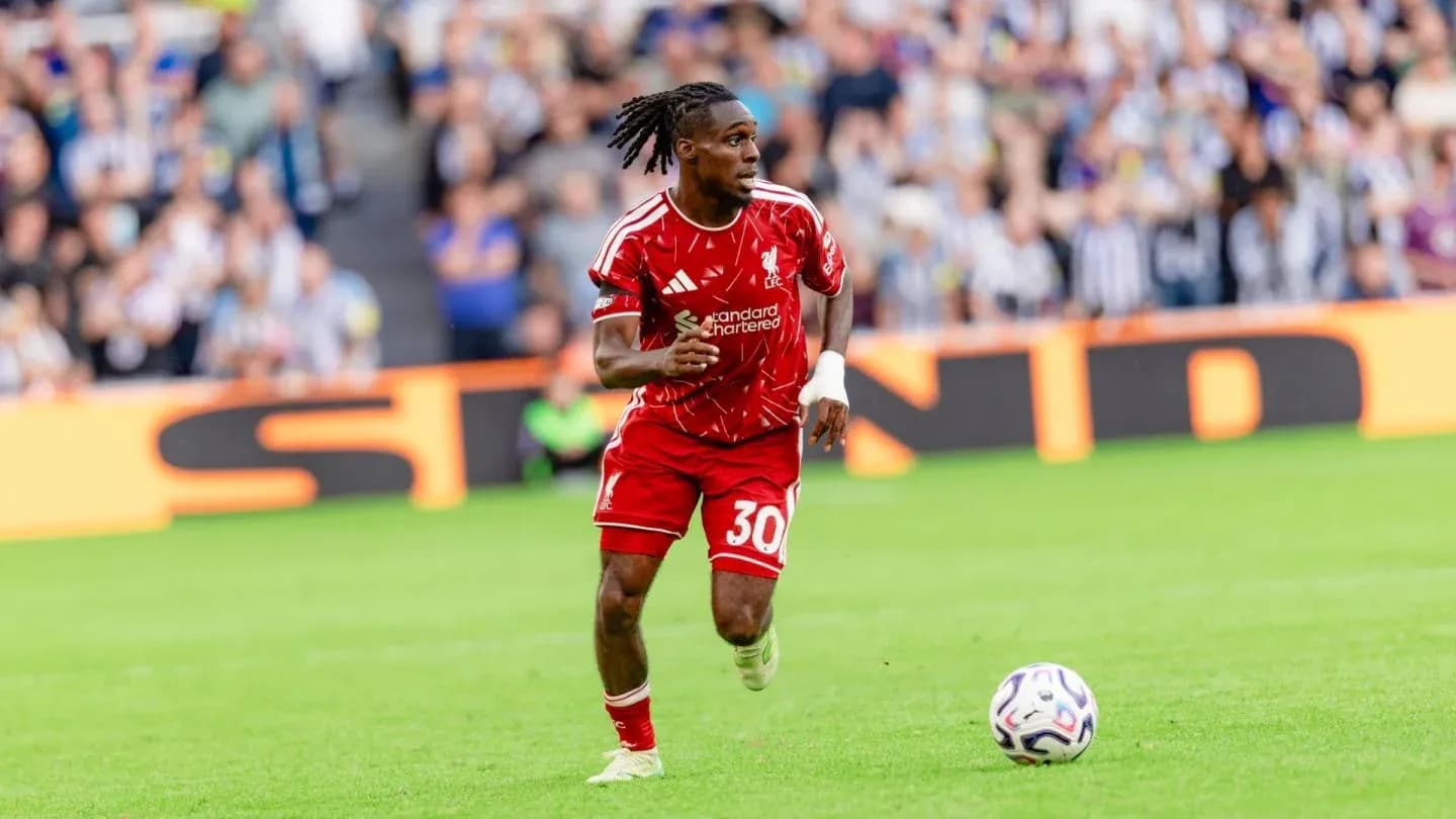 Player in red kit running with soccer ball on field