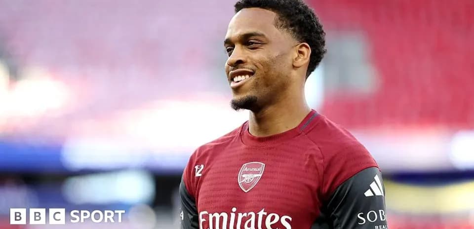 Player in Arsenal training kit smiling on field