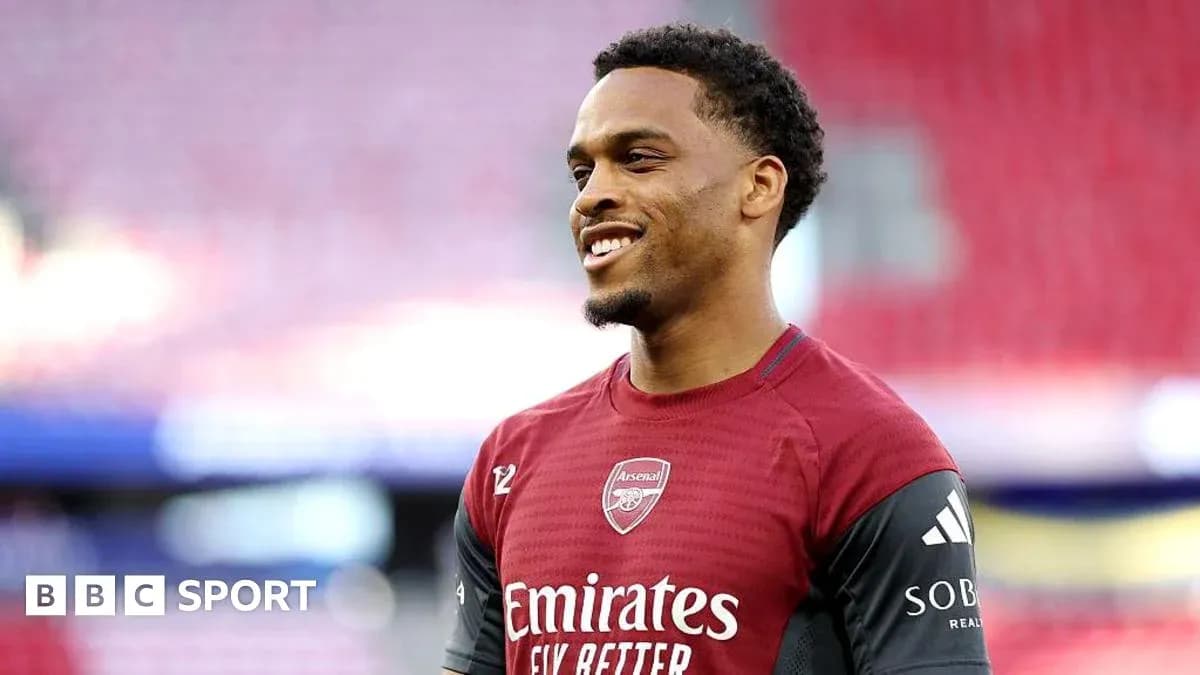 Player in Arsenal training kit smiling on field