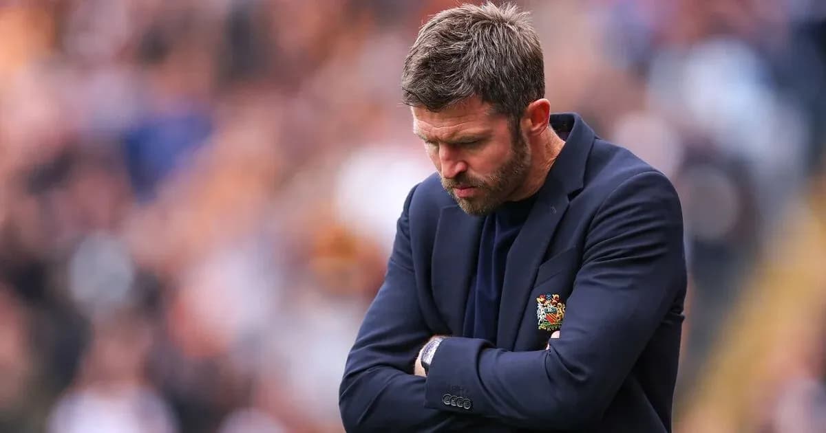 Coach looking down with arms crossed during match