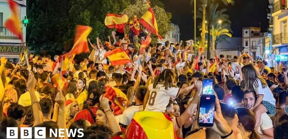 Crowd celebrating with flags in a street at night