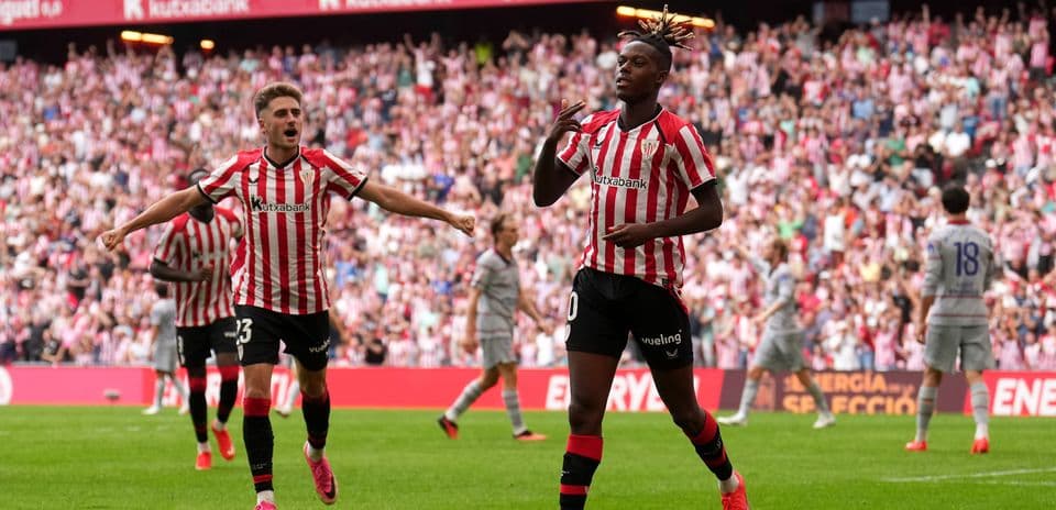 Player celebrating goal with teammates in stadium