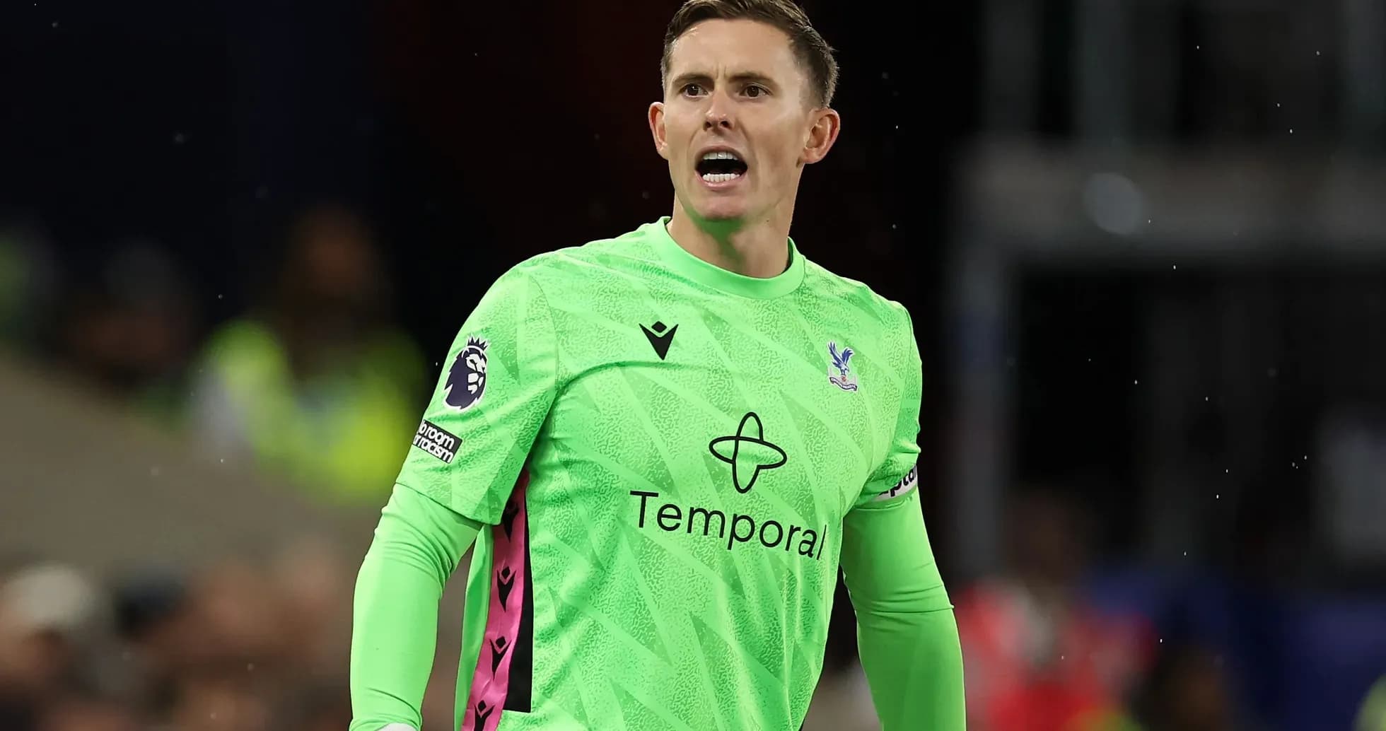 Goalkeeper in green jersey directing players on field
