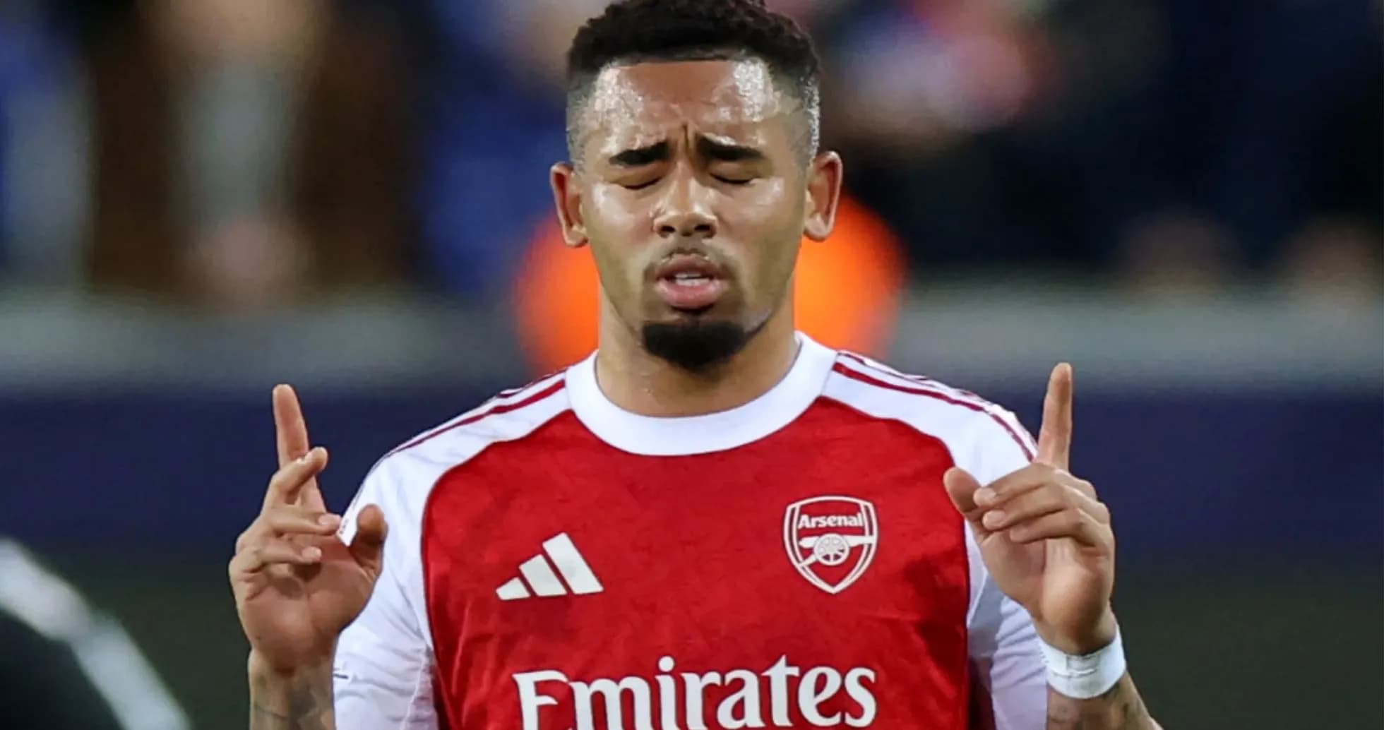Player with Arsenal jersey holding hands up in prayer