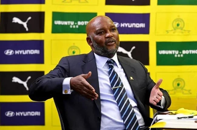 Coach speaking during press conference with team branding