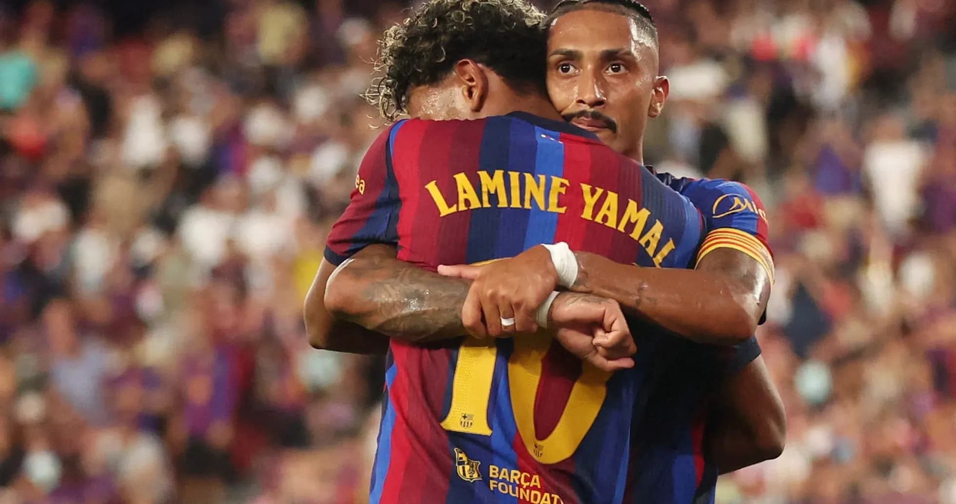 Two FC Barcelona players embracing on the pitch