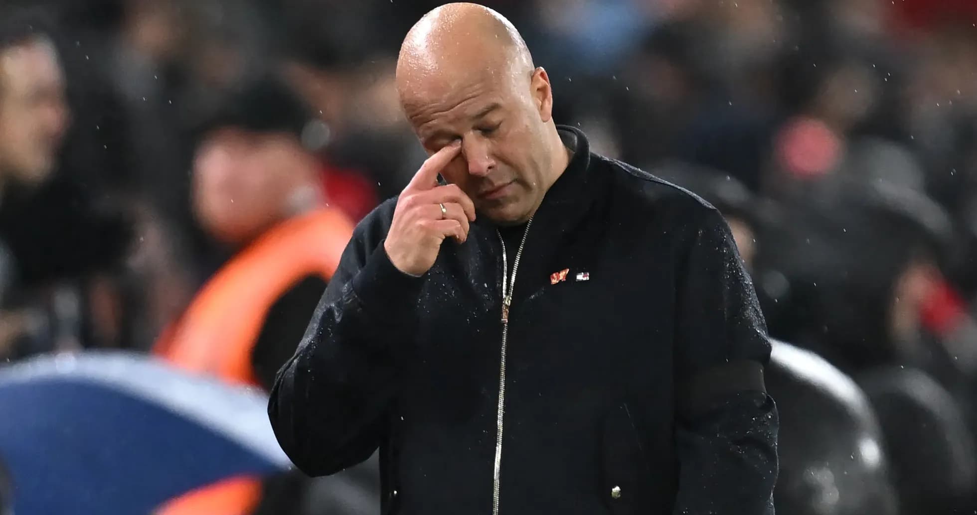 Coach wiping brow during rainy match atmosphere