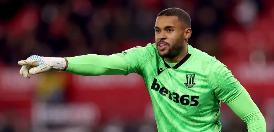 Goalkeeper in green kit directing teammates during match
