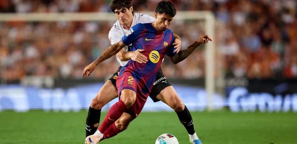 Barcelona player challenged by Valencia defender during match