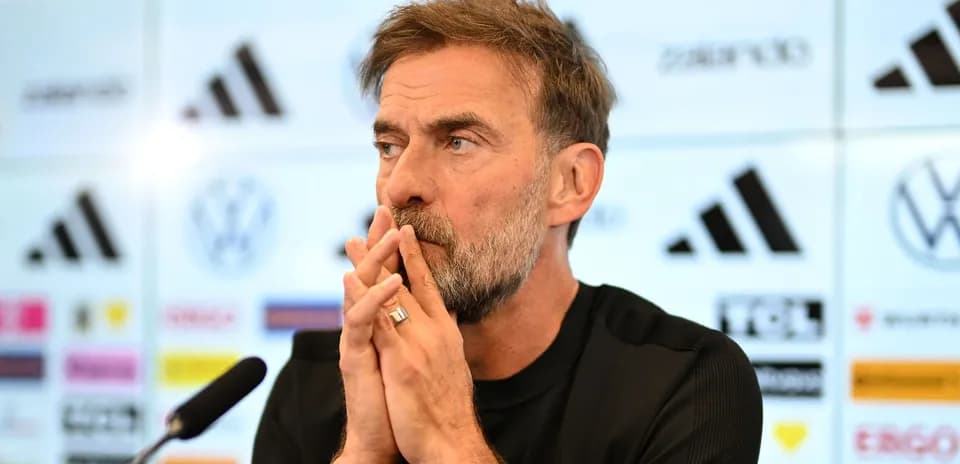 Manager speaking at press conference with logos behind