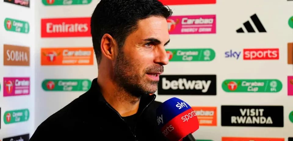Manager speaking during press conference with sponsor logos