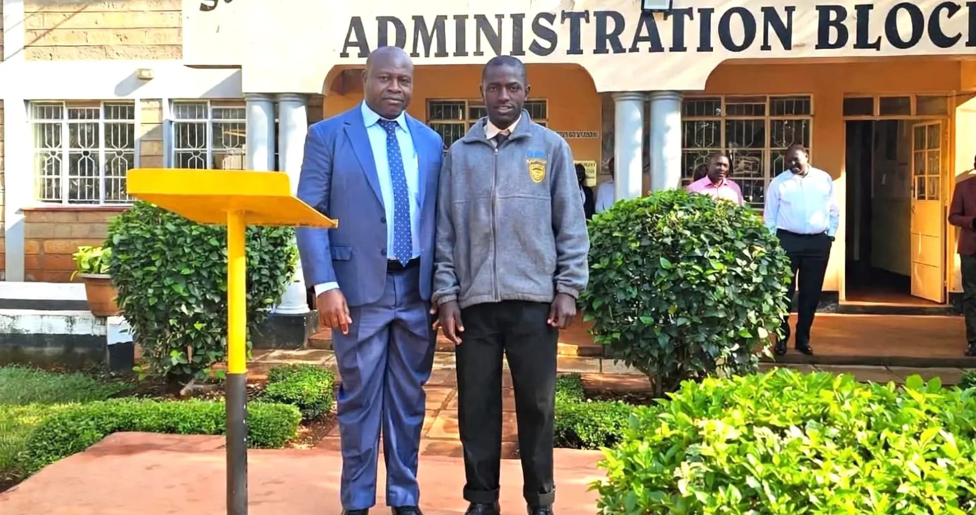 Two men posing outside St. Anthony's Boys' High School