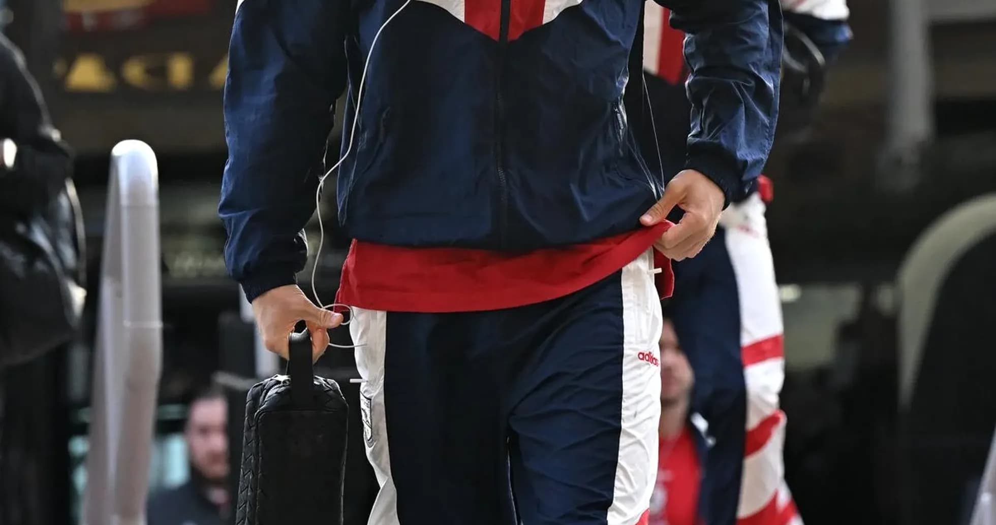 Player in tracksuit arriving at venue with bag