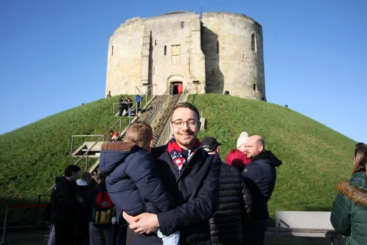 Man holding child in front of historic tower