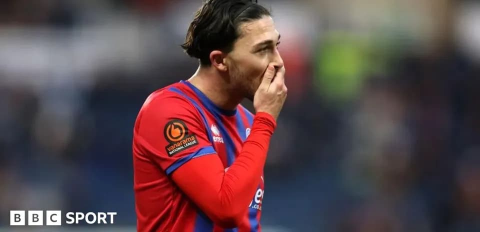 Player in red and blue kit touching his face