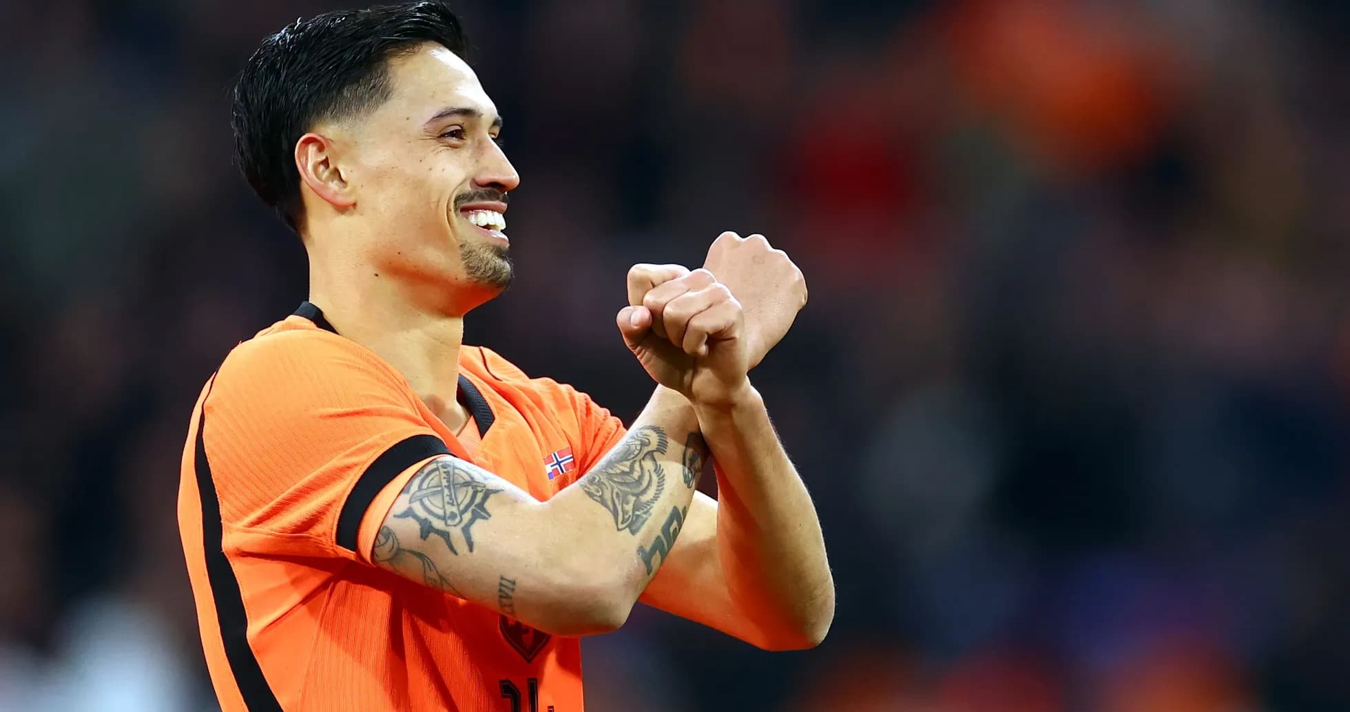 Player celebrating in orange jersey with tattoos