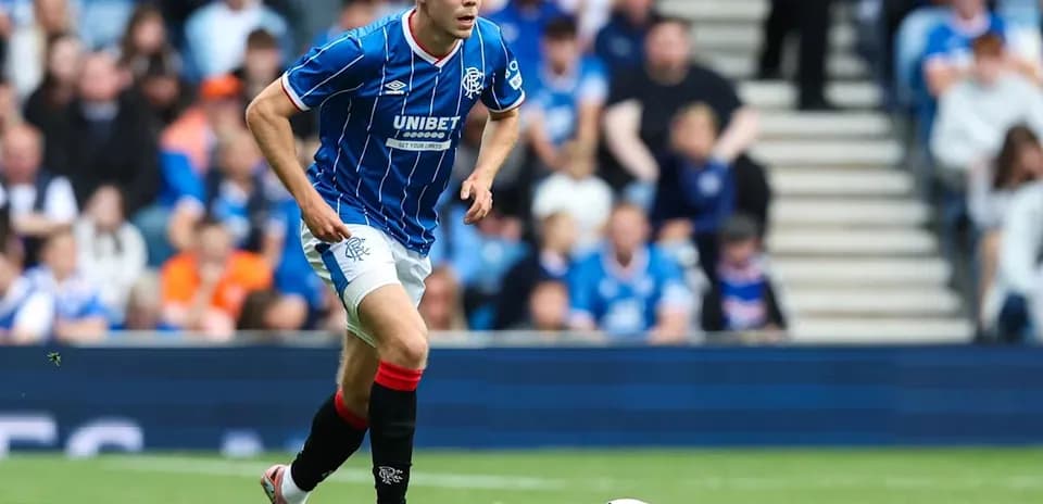 Rangers player running with ball on pitch