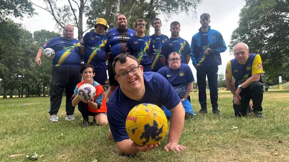 Group of players posing with footballs in park