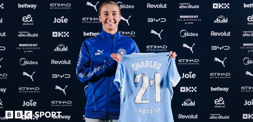 Player holding Manchester City jersey during signing event