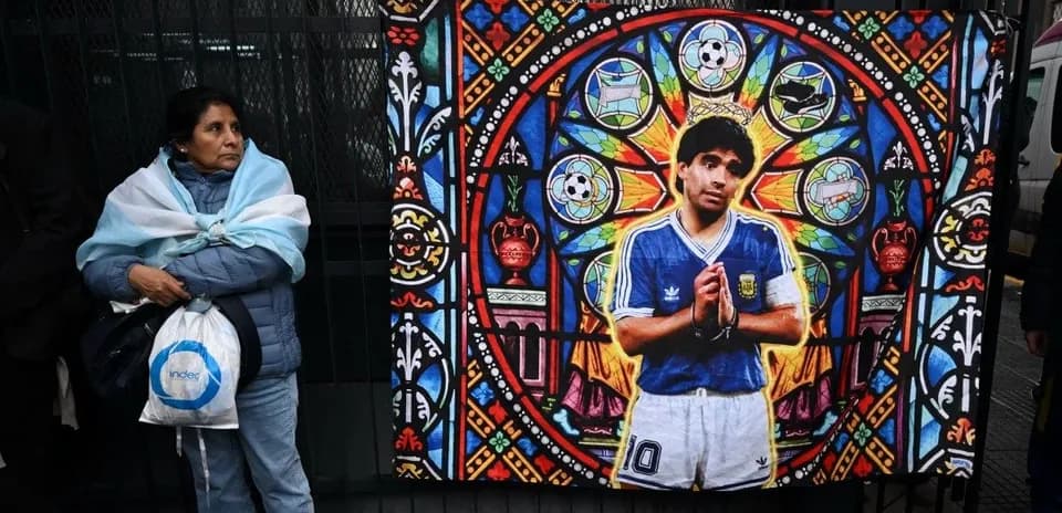 Woman standing beside mural of Diego Maradona