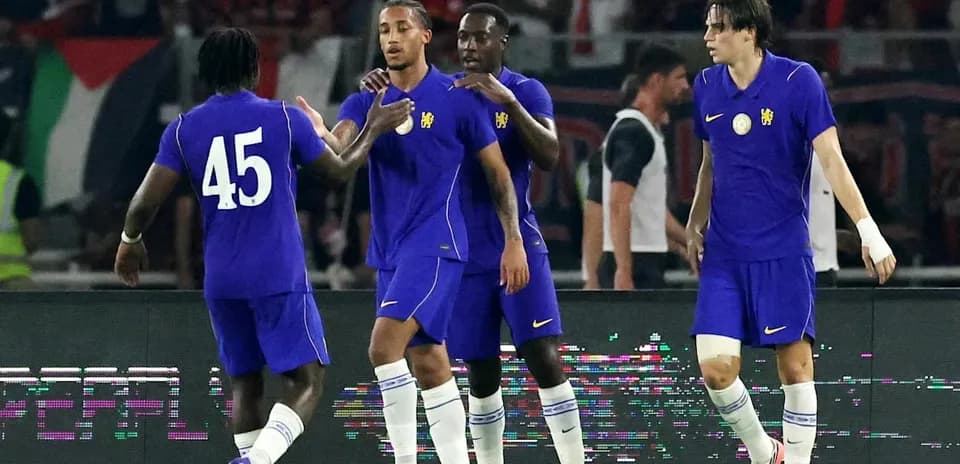 Four players in purple jerseys celebrating on field