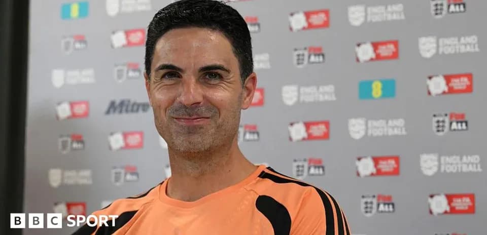 Coach smiling during press conference with backdrop