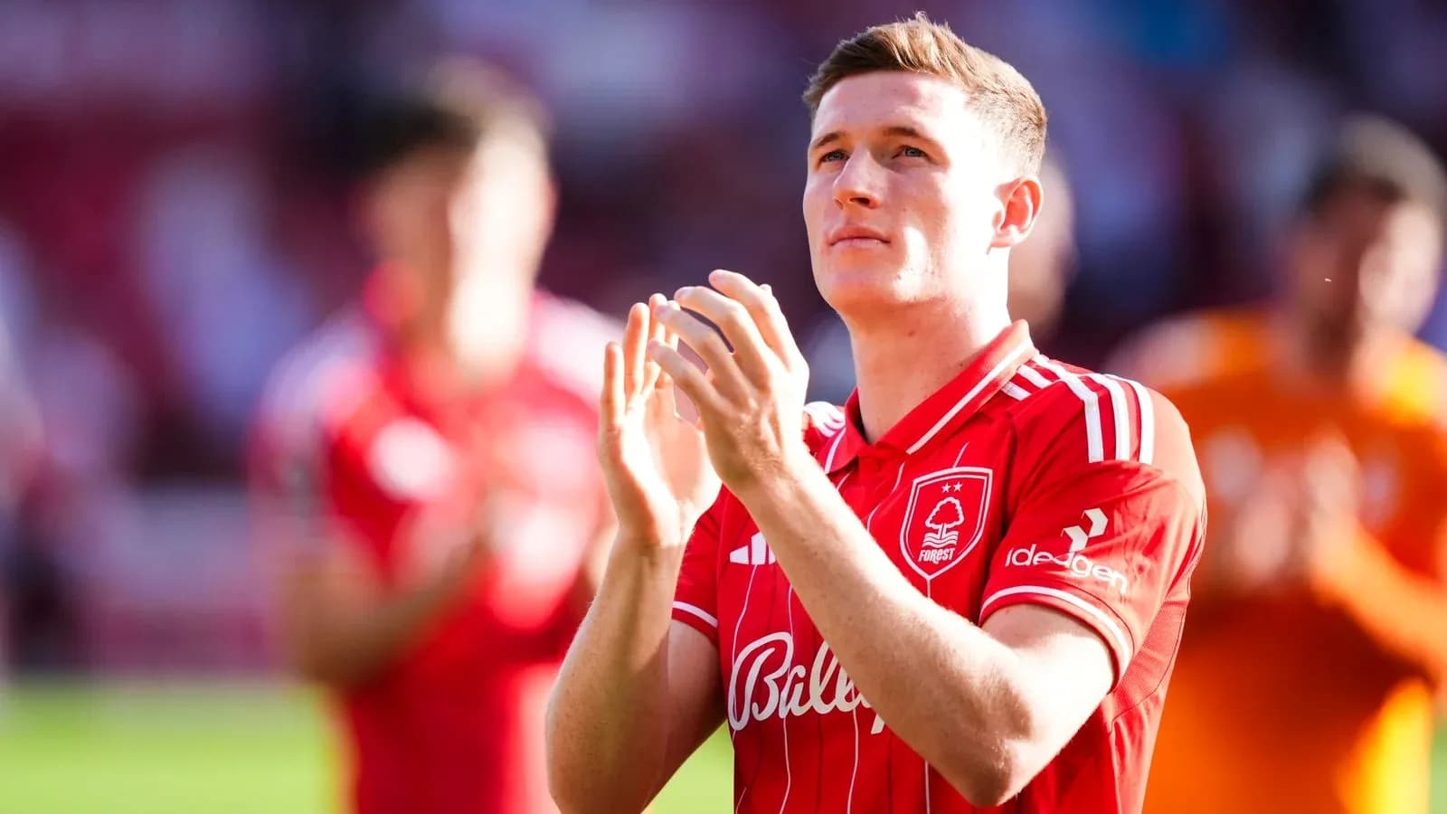 Player applauding fans while wearing red jersey