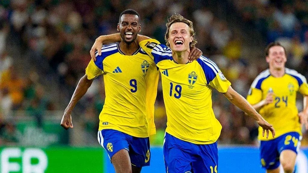 Two Swedish players celebrating a goal on field