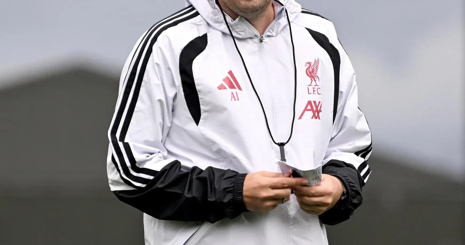 Coach walking on training pitch wearing Liverpool kit