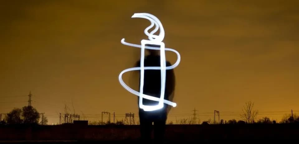 Person creating light art in dark landscape