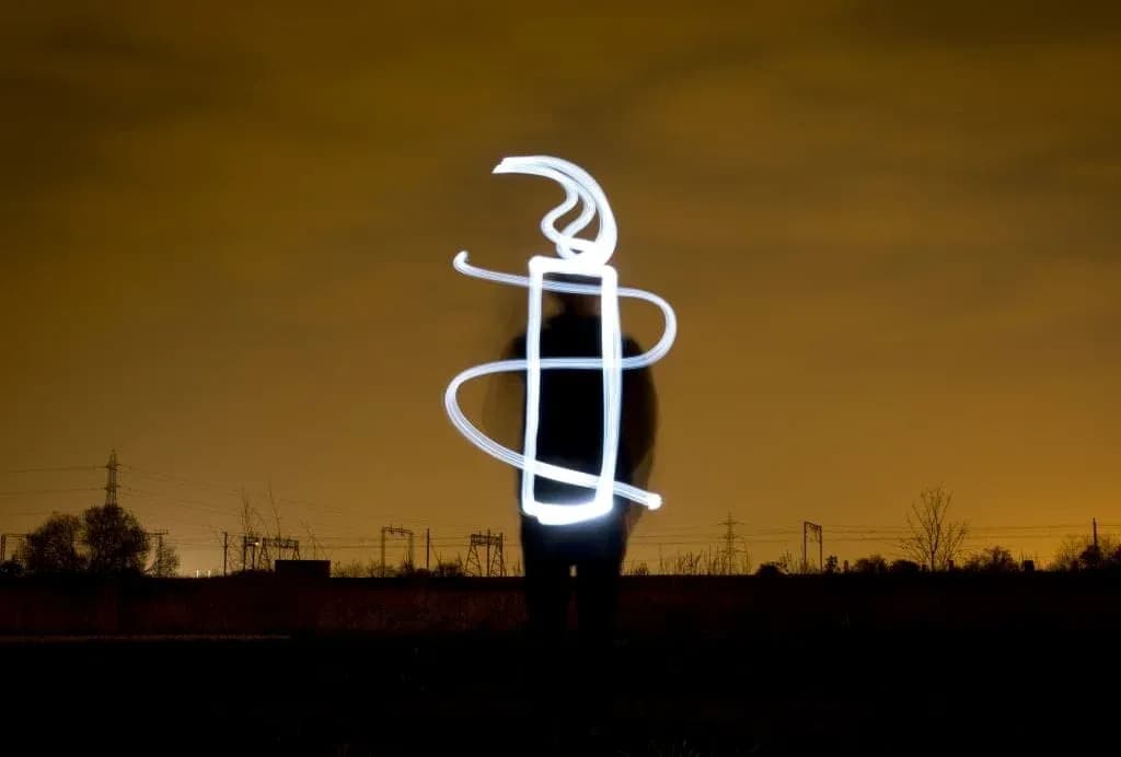Person creating light art in dark landscape