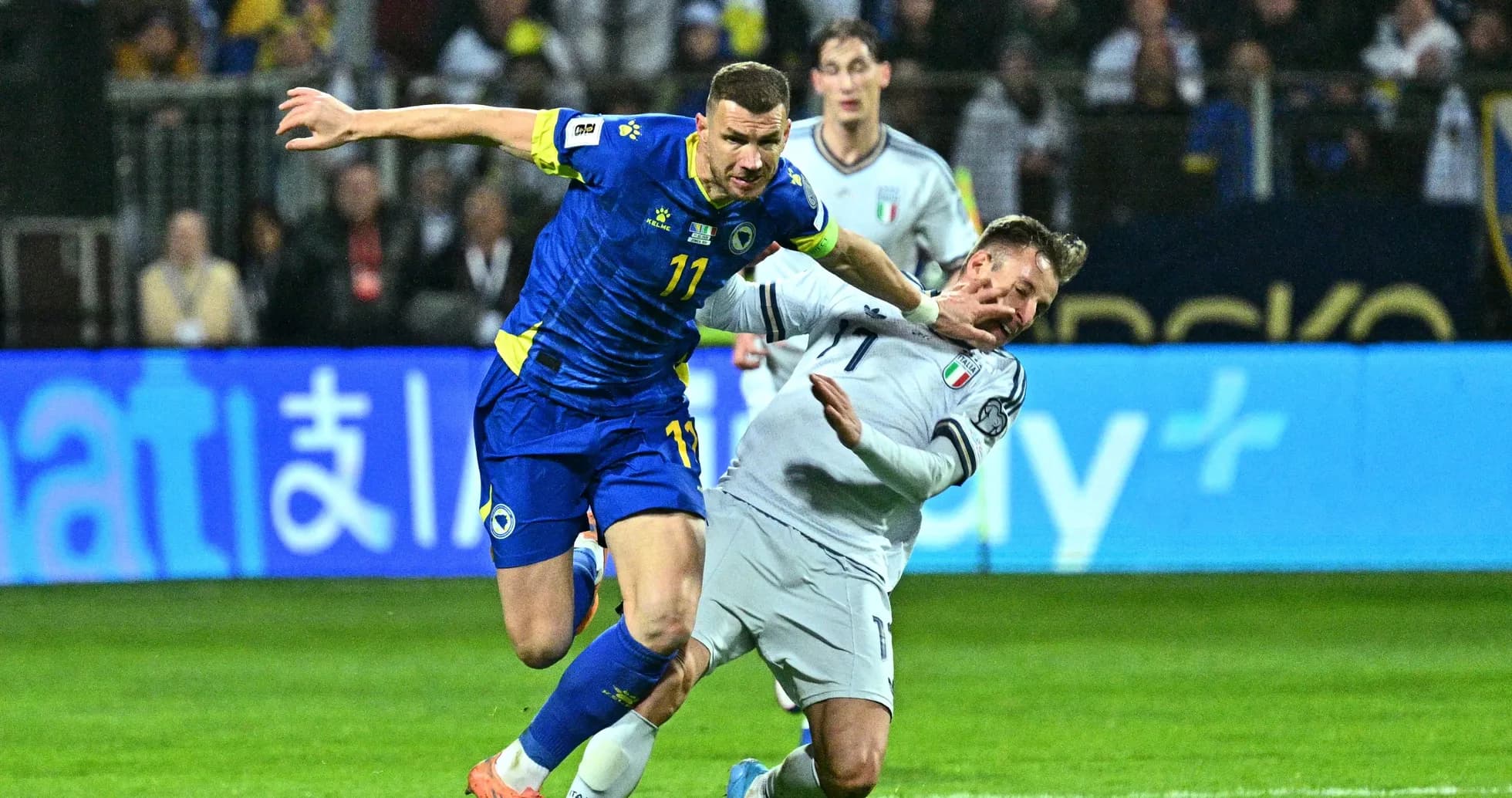 Player from Bosnia challenging Italian defender during match