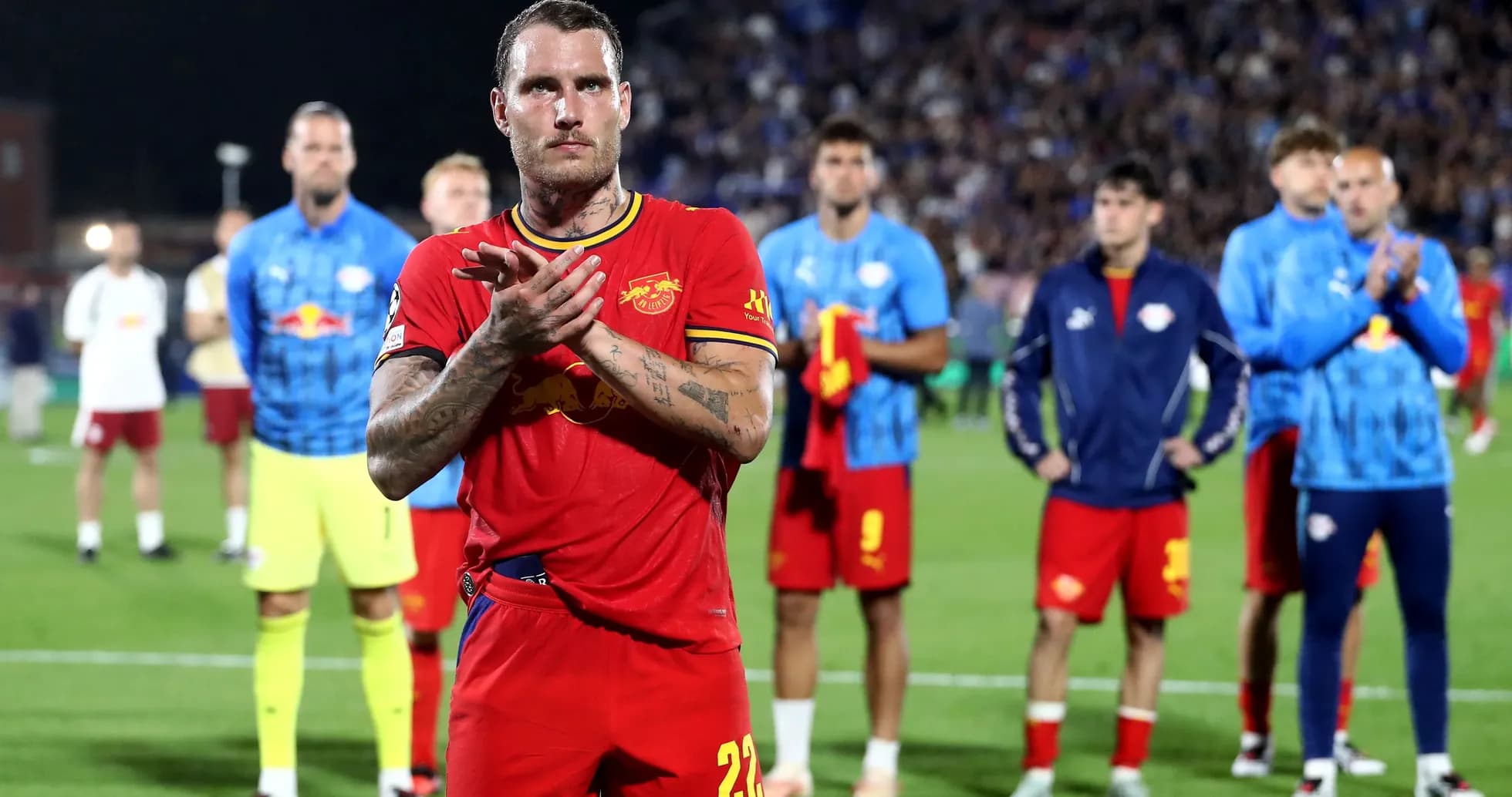 Player applauding with teammates in background after match