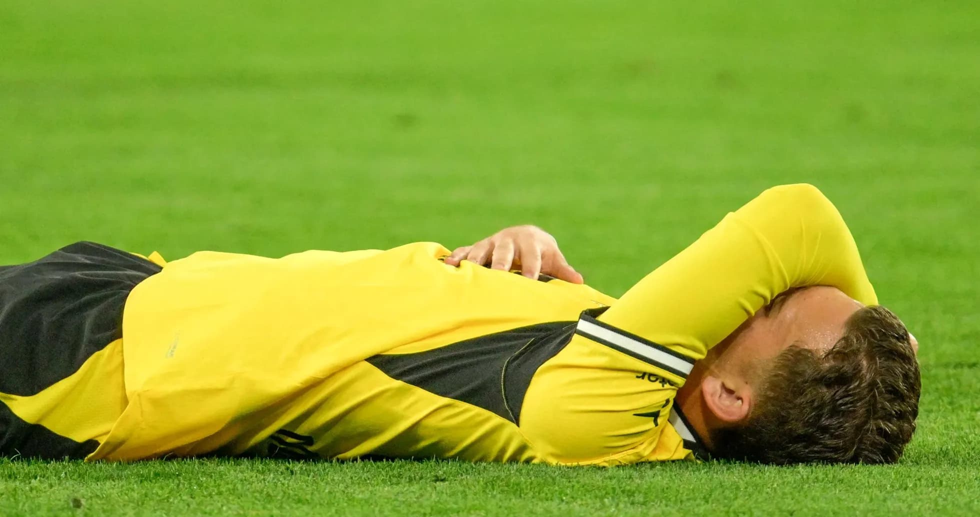 Player lying on the field in yellow jersey