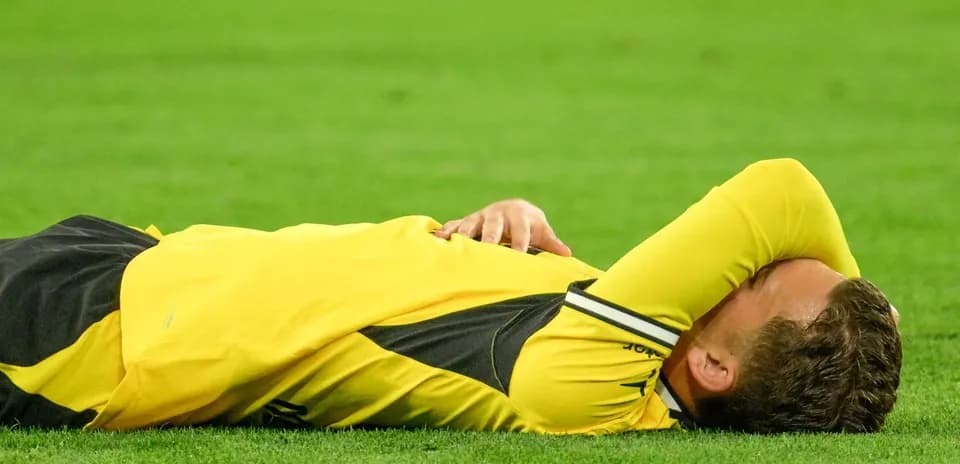 Player lying on the field in yellow jersey